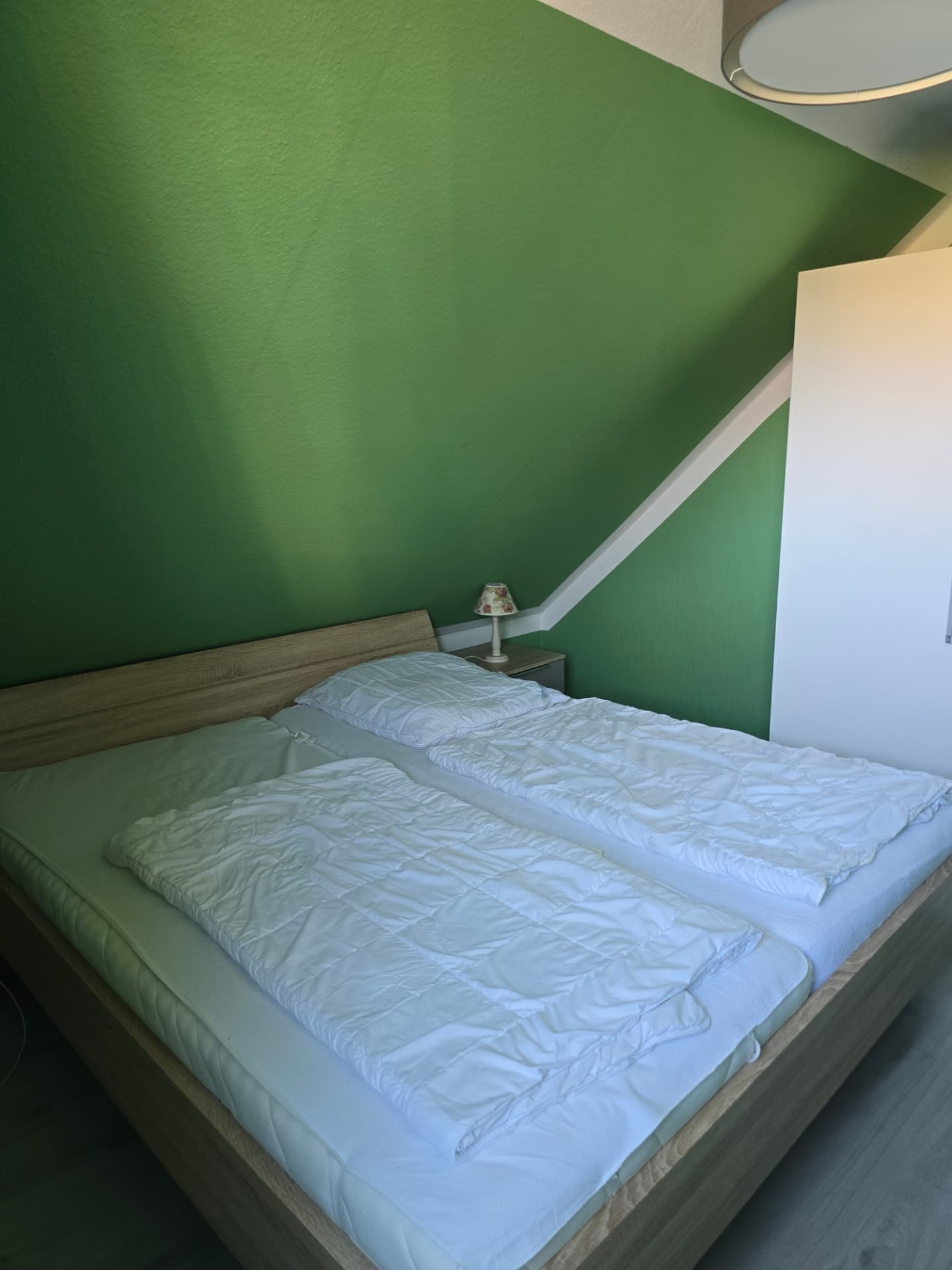 Schlafzimmer in Grüntönen mit Einzelbett und Fenster in der Muscheln Wohnung