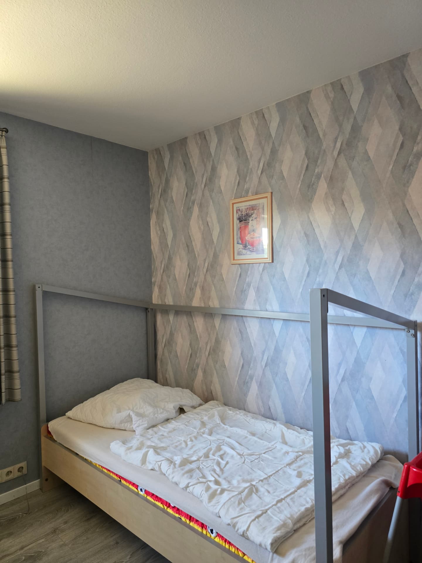 Kinderzimmer mit Einzelbett und gemusterter Tapete im See Möwe Haus