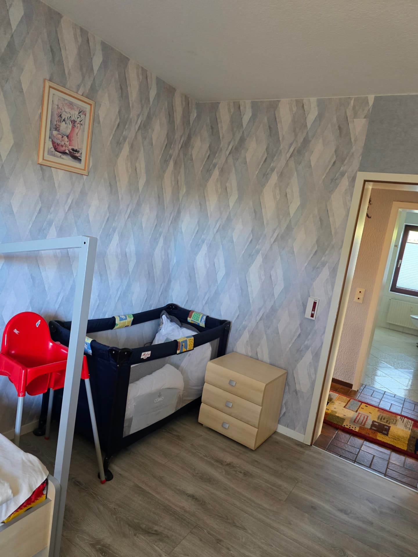 Kinderzimmer mit Reisebett, Kinderstuhl und Kommode
