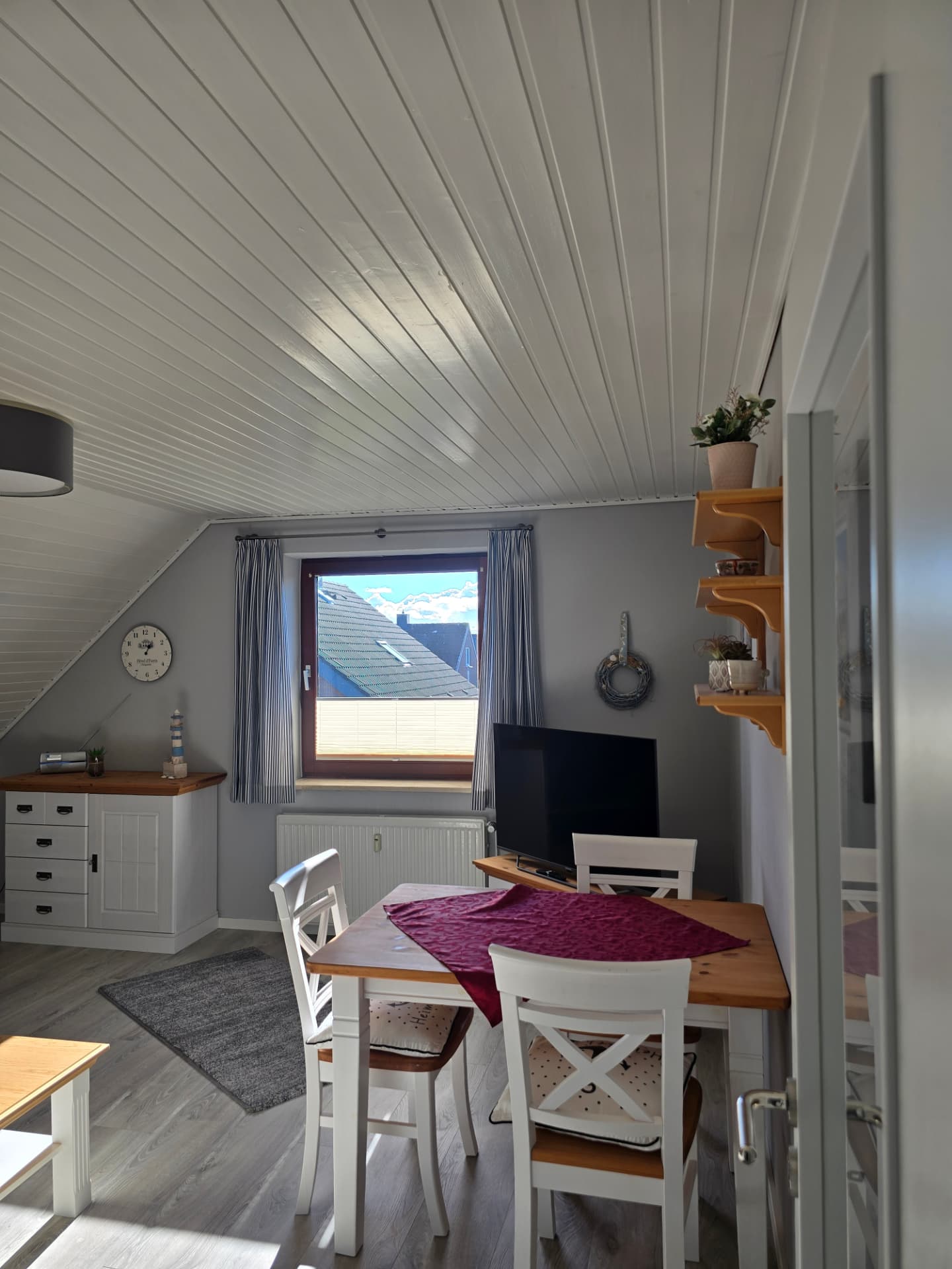 Essbereich mit Holztisch, weißen Stühlen, Kommode und Fenster im See Adler